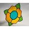 A bright stained glass yellow flower with teal center and green leaves, on a neutral background