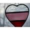 Stained glass heart in red, rose and clear stripes with nature in the background