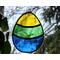 Stained glass Easter Egg on nature background, featuring yellow, green, and blue stripes
