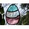 Stained glass Easter Egg on a nature background, featuring pastel teal, clear, and plum stripes