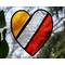 Stained glass heart with red, clear, and orange stripes with nature in the background