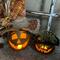 This image shows two Halloween pumpkins lit with candles. They are hand-carved gourds. Each pumpkin has a custom hat.