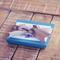 Turquoise blue jewelry gift box with gift tag and silver ribbon on natural wood background jewelry packaging example. 