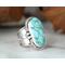 Large turquoise blue ovalish stone with embellished setting on a thick wide tapered band with a light patina. Size 9.5