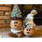 This is a picture of two Christmas gourd decorations. They are made to look like elves with happy faces carved into the gourd shells. 