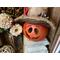 This image shows a fall display with a carved pumpkin gourd decoration. It has a happy face carved into the shell and a hand made fall hat.