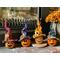 These are fall gourds carved like pumpkins. They are all have a handmade witch hat. They decorate a fireplace hearth. 