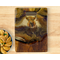 A handcrafted serving board made from salvaged teak with cutout handle. Rich, warm resin artwork with a highland cow and ribbons of 24K gold