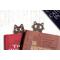 Pair of cat bookmarks peeking at each other from within two books.