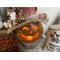 This image shows a Halloween witch decoration. It is carved like a pumpkin with a battery-operated candle liting up her smile. 