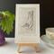 OEV-2 photo of Hand-Incised Intaglio Print White-Breasted Nuthatch next to teacup for size reference, print is 3-3/4" wide x 4-1/8" tall
