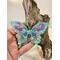 resin butterfly sun catcher hanging on natural wood in adult size hand