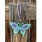 Resin butterfly sun catcher full view hanging on outdoor wood fence post.