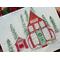 Watercolor and ink art print of Santa's red Workshop decorated for Christmas, featuring a separate building with Santa's sleigh inside. 