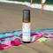A Beach Vibes roll-on wellness blend by Whole Self Aromatherapy on a sandy beach with grass and the ocean in the blurred background.