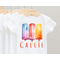 White baby bodysuit with three watercolor popscicles blue purple red yellow hues. baby name across bottom in orange print font.