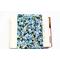 A padded book sleeve on top of an open book. The book sleeve is made with a blue floral Rifle Paper Co. cotton print.