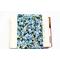 A padded book sleeve on top of an open book. The book sleeve is made with a blue floral Rifle Paper Co. cotton print called Garden party.