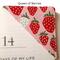 A corner bookmark on the top corner of a book. Made with a print with red and white strawberries on a pink background.