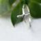 Sleek sterling silver sideways cross ring on white background.

