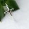 Sleek sterling silver sideways cross ring on white background.
