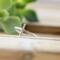 Sleek sterling silver sideways cross ring on wood background.
