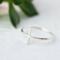 Sleek sterling silver sideways cross ring on white background.

