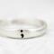 Sterling silver semicolon awareness ring with subtle symbol, on white surface. 
