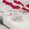 Sterling silver diamond cut rings on white holder, red flowers in background, 1.5mm wide, gift-ready.  
