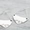 Handcrafted sterling silver fern-stamped hoop earrings on a wooden surface, showcasing elegant leaf designs. 
