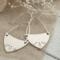 Handcrafted sterling silver fern-stamped hoop earrings on burlap with white flowers, made in Soldotna, Alaska. 

