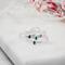 Four dainty sterling silver stacking rings with green, blue, and pink cubic zirconia birthstones, displayed on a white marble surface.
