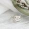  Three sterling silver stackable rings with lowercase initials "a," heart, and "t" on a white  background with dried flowers
