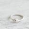  Three sterling silver stackable rings with lowercase initials "a," heart, and "t" on a white  background with dried flowers
