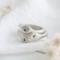  Three sterling silver stackable rings with lowercase initials "a," heart, and "t" on a white  background with dried flowers
