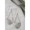 Sterling silver trillion shape imprinted with a mandala design hanging from sterling silver chain from two corners and a sterling ear wire. 
