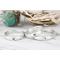 Sterling silver heart and cross rings on a white wood surface with floral background. 