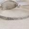 Handcrafted sterling silver wildflower oval cuff bracelet from Alaska, with textured band, on floral paper. 
