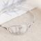 Handcrafted sterling silver wildflower oval cuff bracelet from Alaska, with textured band, on floral paper. 
