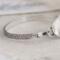 Handcrafted sterling silver wildflower oval cuff bracelet from Alaska, with textured band, on floral paper. 
