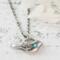 Sterling silver bird necklace with turquoise, on a white surface.
