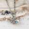 Sterling silver bird necklace with turquoise, on a white surface.
