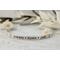 Sterling silver cuff bracelet stamped with kids names in a delicate handwritten font with a stamped for detail on both sides.