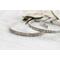 A pair of sterling silver cuff bracelets with an embossed floral pattern, displayed on a rustic white wooden surface.