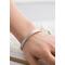 A close-up of a sterling silver floral cuff bracelet worn on a wrist, showcasing its elegant design and fit.