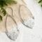 Handcrafted sterling silver Art Nouveau floral hoop earrings on a textured background with greenery.
