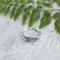 Close-up of vintage sterling silver leaf ring on white wood, eco-friendly, sizes 3-10.  
