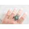 Silver ring with pear-shaped faceted labradorite featuring blue-green opalescent flashes serrated bezel and bead detailing around the bezel.
