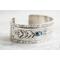 Sterling silver cuff bracelet with embossed arrow overlay accented with a genuine turquoise cabochon. 