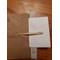 One bone nalbinding needle, atop its packaging prior to shipping.